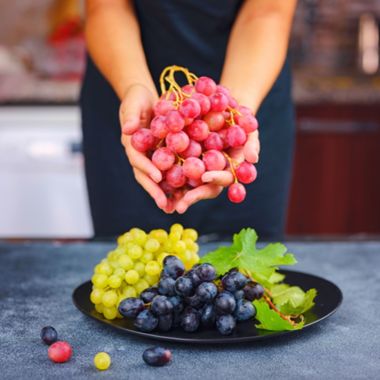 bundles of grapes on a plate and in hands